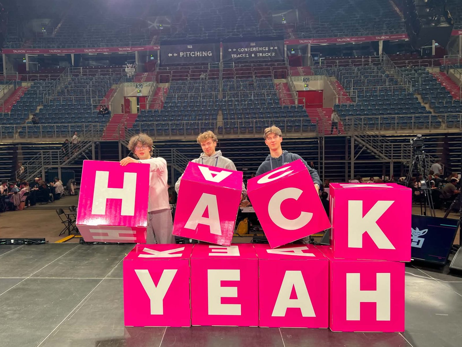 Jakub Siuda and teammates with the pink HACK YEAH letters at HackYeah 2026 in TAURON Arena Kraków