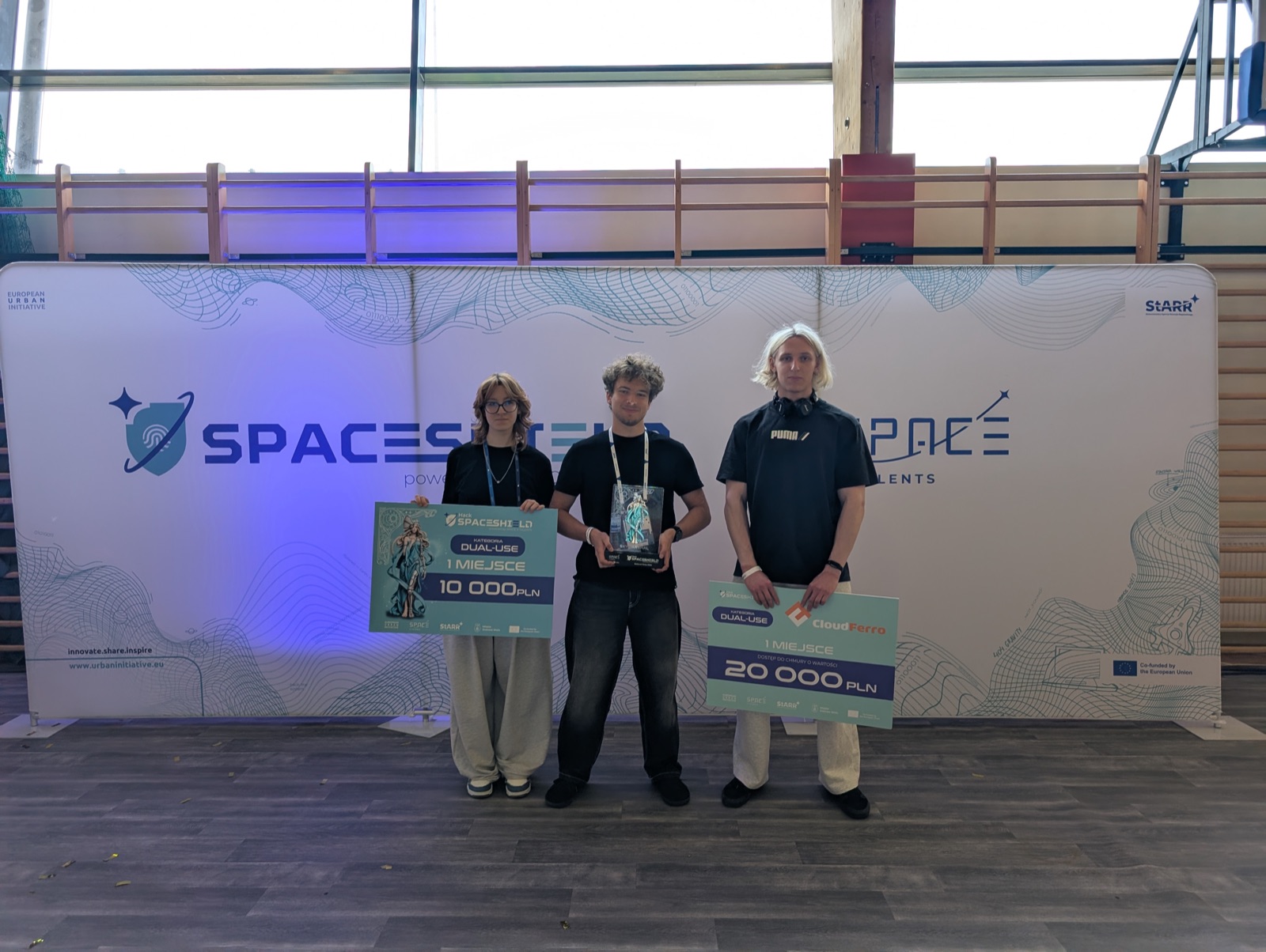 Jakub Siuda standing in the middle of team 404 with the SpaceShield Hack winner trophy and award boards